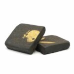 Detailed description: A close-up of black hash candies with a gold skull logo on top, showcasing premium cannabis-infused edibles from Great Canadian Buds, perfect for recreational or medicinal use.