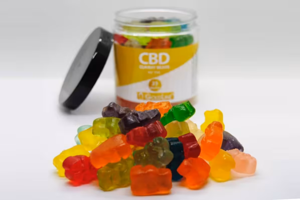 Vibrant CBD gummies in various colors and flavors, placed near a jar labeled "CBD" on a white surface. Perfect for natural health, stress relief, and medicinal use from Great Canadian Buds.