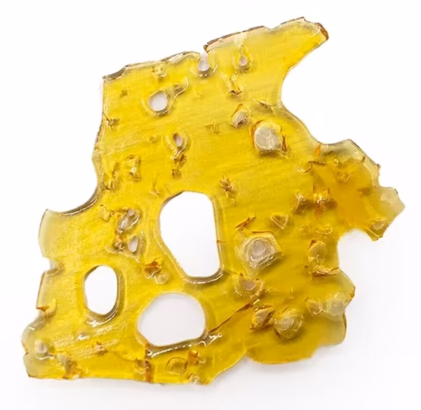 Close-up of a yellow cheddar cheese hash cake with a crispy texture and holes, highlighting its appeal as a Canadian edible cannabis product infused with rich flavor and potency.