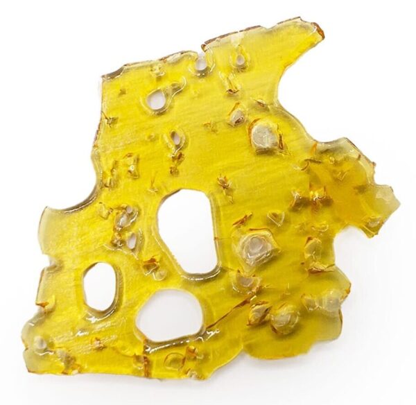 Close-up of a yellow cheddar cheese hash cake with a crispy texture and holes, highlighting its appeal as a Canadian edible cannabis product infused with rich flavor and potency.
