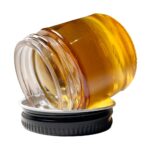 High-quality cannabis concentrate oil in a glass jar, featuring vibrant amber color, ideal for medicinal and recreational cannabis consumers seeking potent, pure THC or CBD extracts.